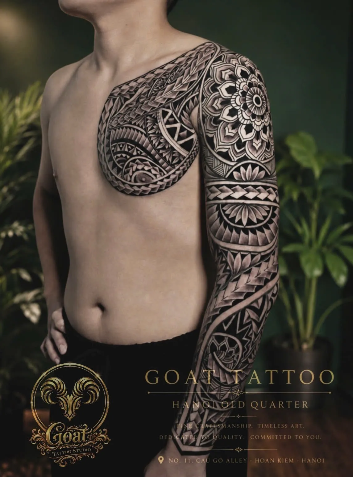 Blackwork Polynesian tribal tattoo with mandala flower detail on the shoulder and arm, by GOAT Tattoo Studio Hanoi.