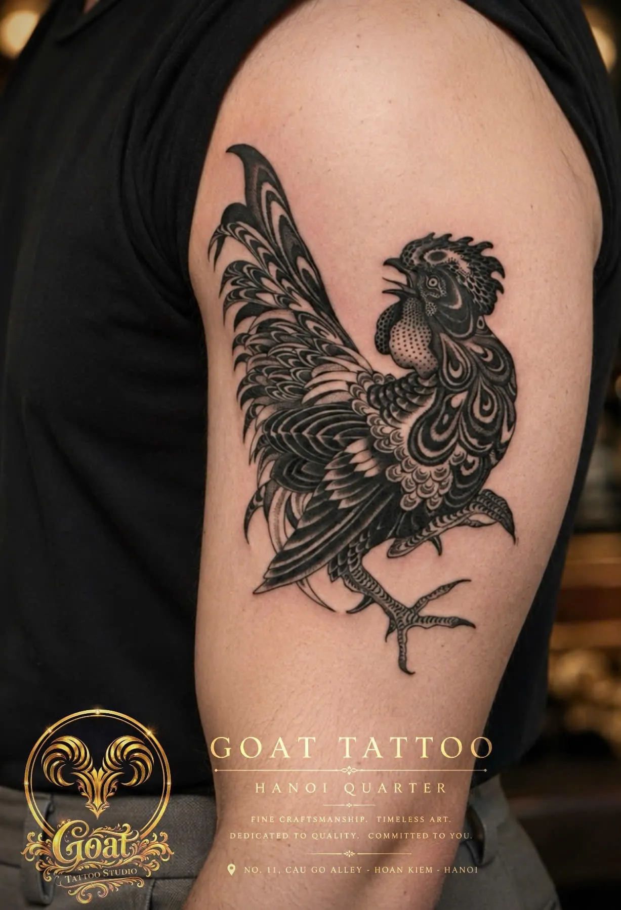 Detailed black rooster tattoo with ornamental feather patterns on the upper arm, by GOAT Tattoo Studio, Hanoi.