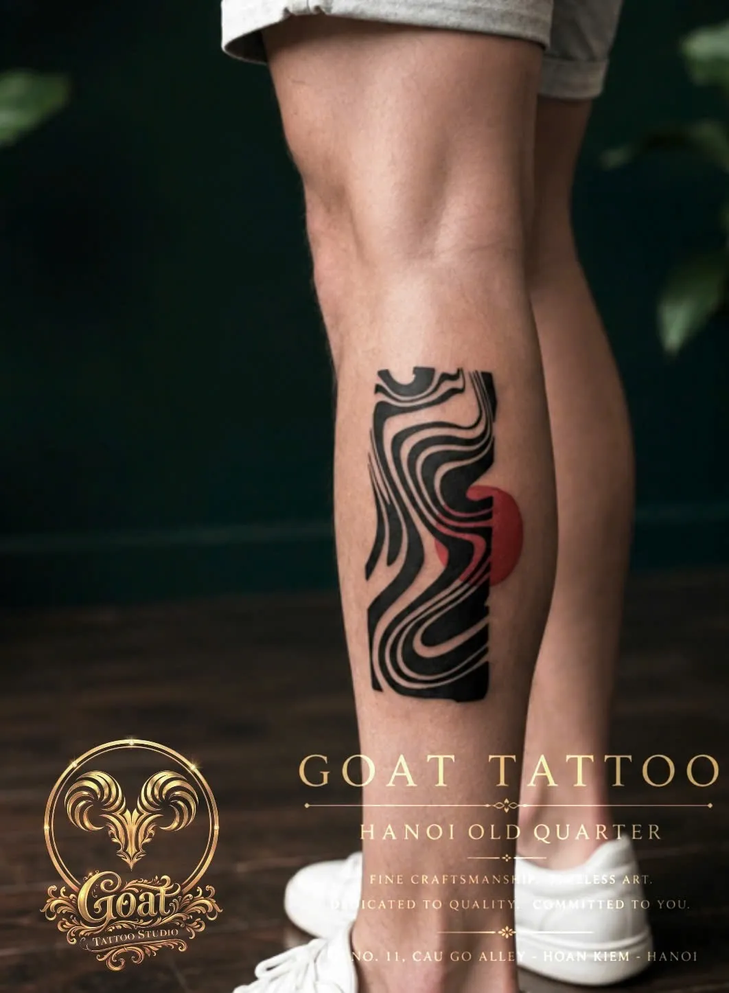 Bold blackwork abstract wave pattern with a red sun accent on the calf, GOAT Tattoo Studio Hanoi.