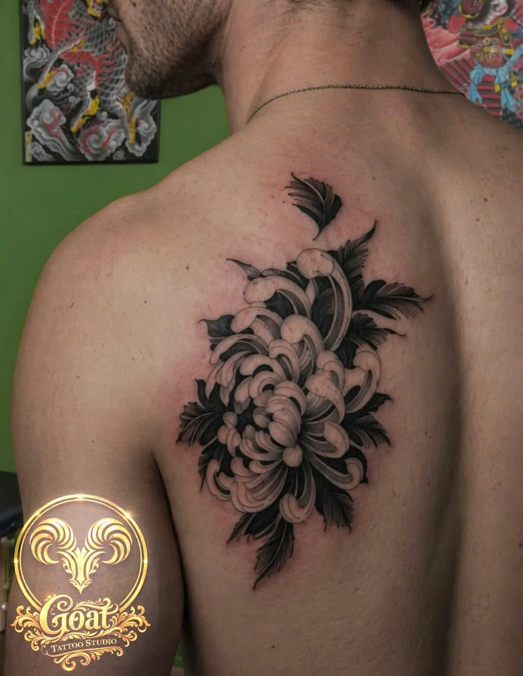 Bold black Japanese-style chrysanthemum flower tattoo covering the shoulder blade, by GOAT Tattoo Studio in Hanoi.