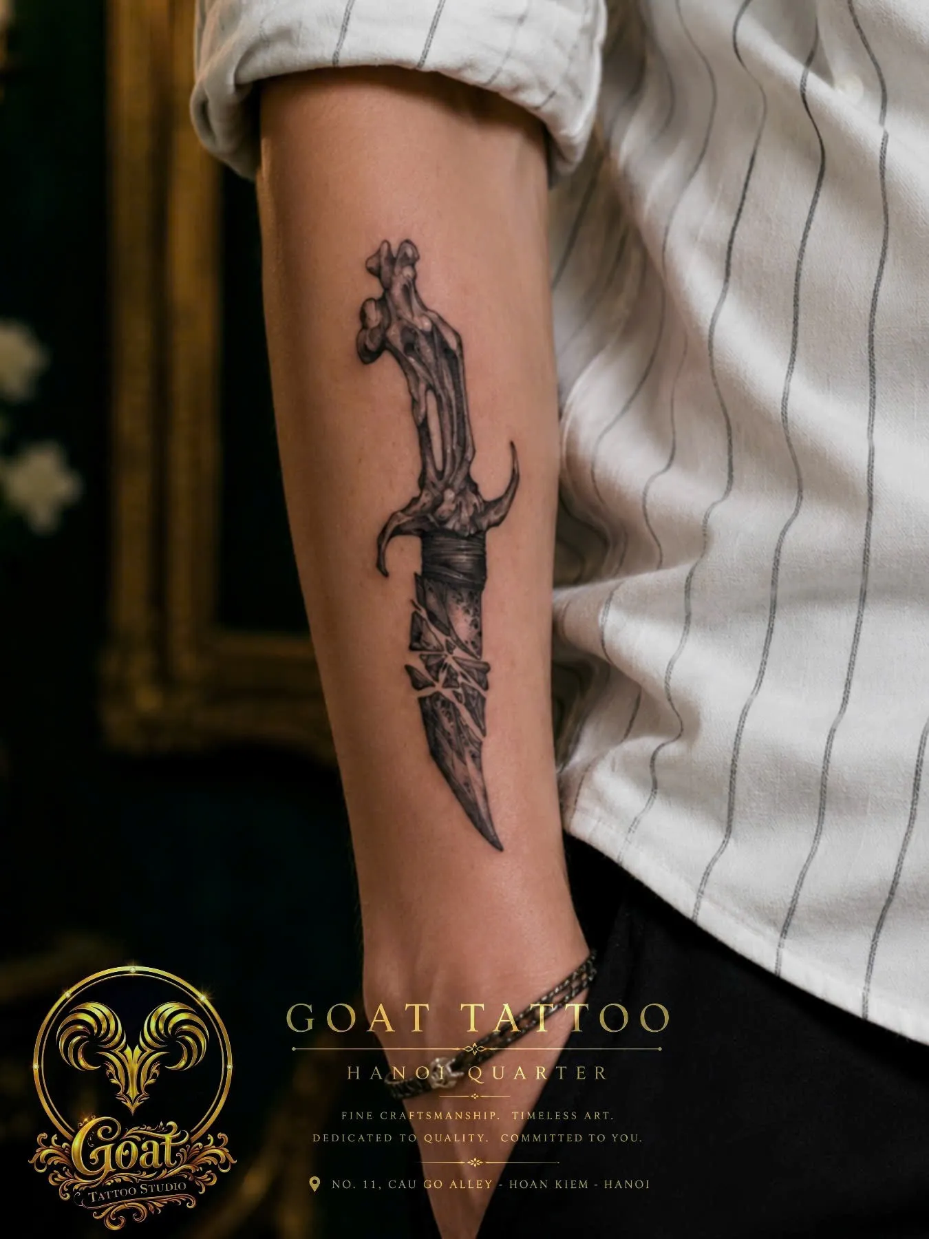 Black and grey bone-handled dagger tattoo detailed along the forearm, by GOAT Tattoo Studio in Hanoi.