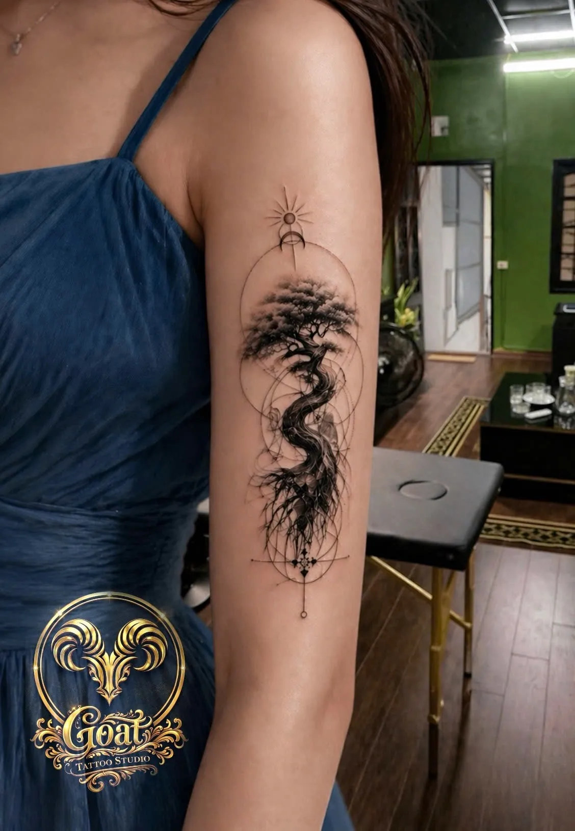 Black and grey bonsai tree tattoo with sun and moon geometric accents on the inner arm, GOAT Tattoo Studio Hanoi.