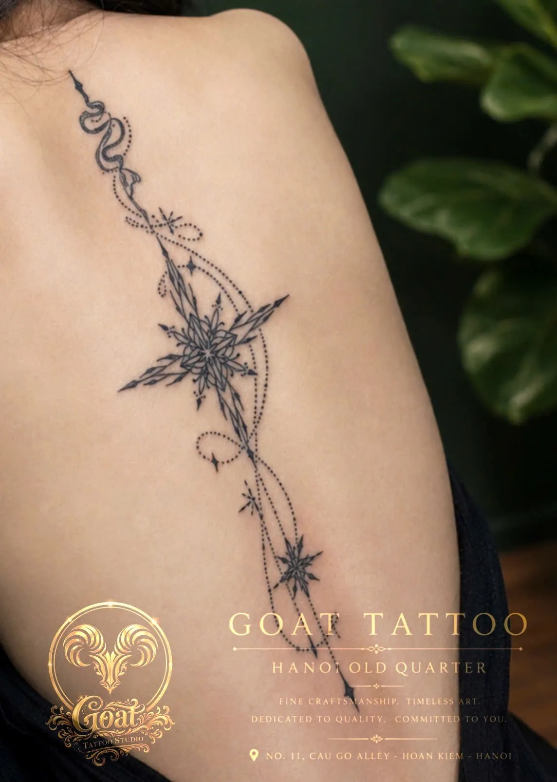 An intricate fine-line tattoo of a snake winding into a radiant star burst and a dotted constellation trail along the spine, done at GOAT Tattoo Studio in Hanoi's Old Quarter.