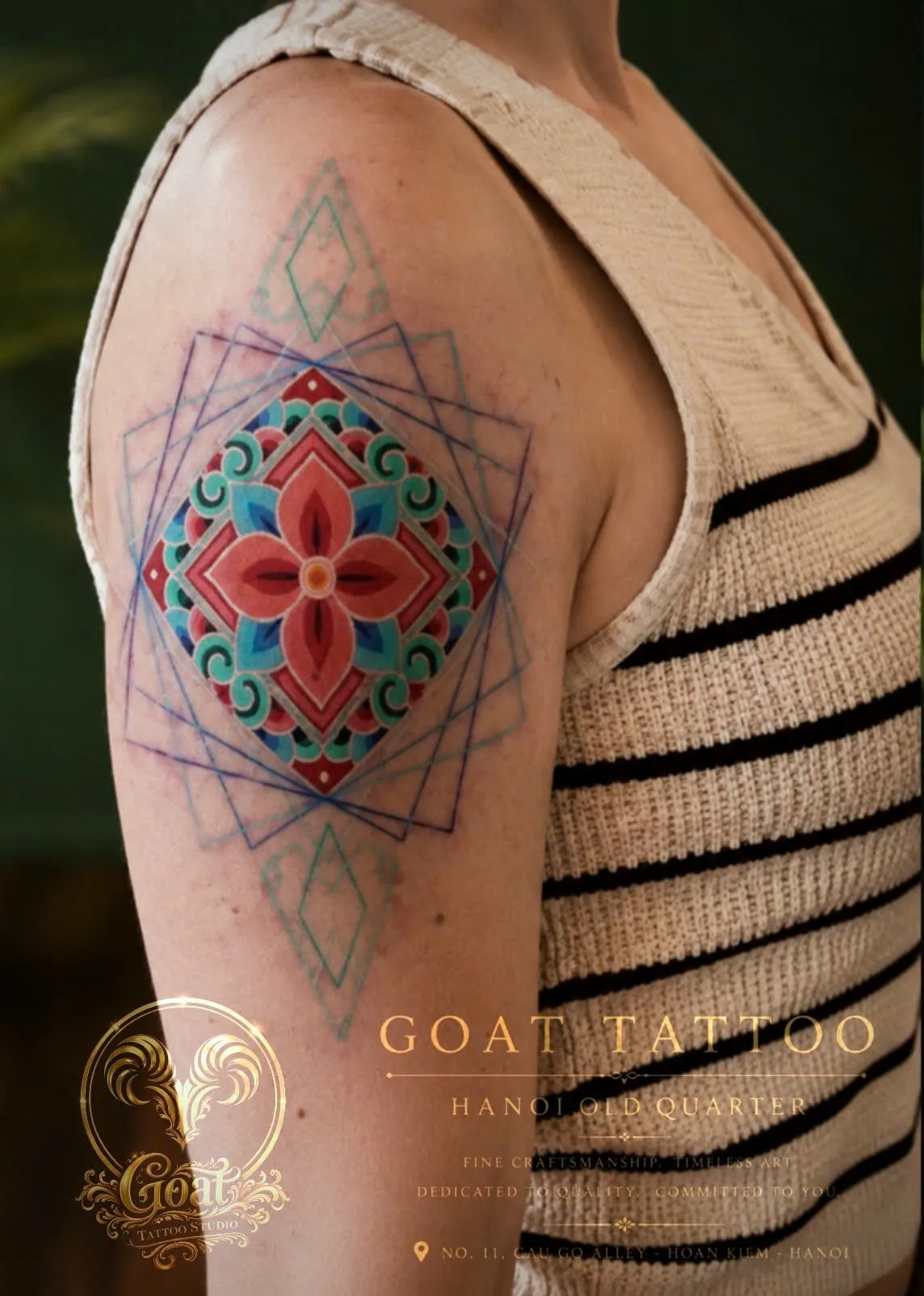 Colorful ornamental mandala tattoo with geometric linework on the upper arm, by GOAT Tattoo Studio Hanoi.