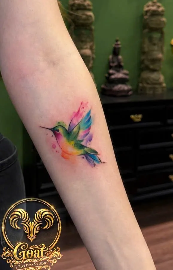 Colorful watercolor-style hummingbird tattoo on the forearm, by GOAT Tattoo Studio in Hanoi's Old Quarter.