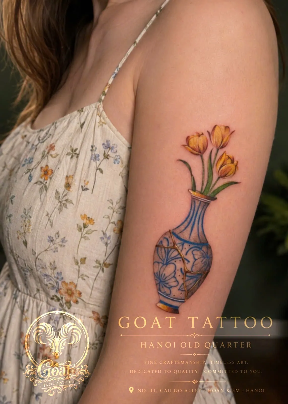 Color illustrative tattoo of a kintsugi-style cracked vase with yellow tulips, on the upper arm, by GOAT Tattoo Studio Hanoi.