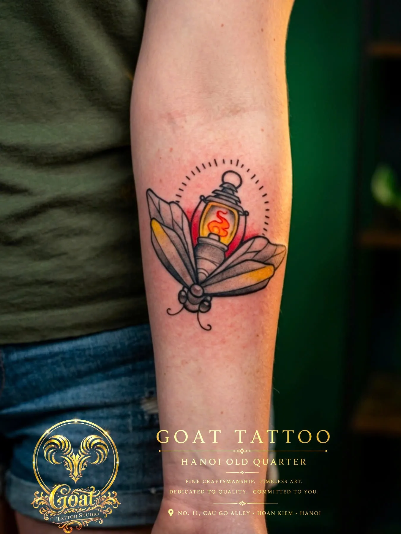 Colorful illustrative tattoo pairing a glowing lantern with a moth on the forearm, by GOAT Tattoo Studio in Hanoi.