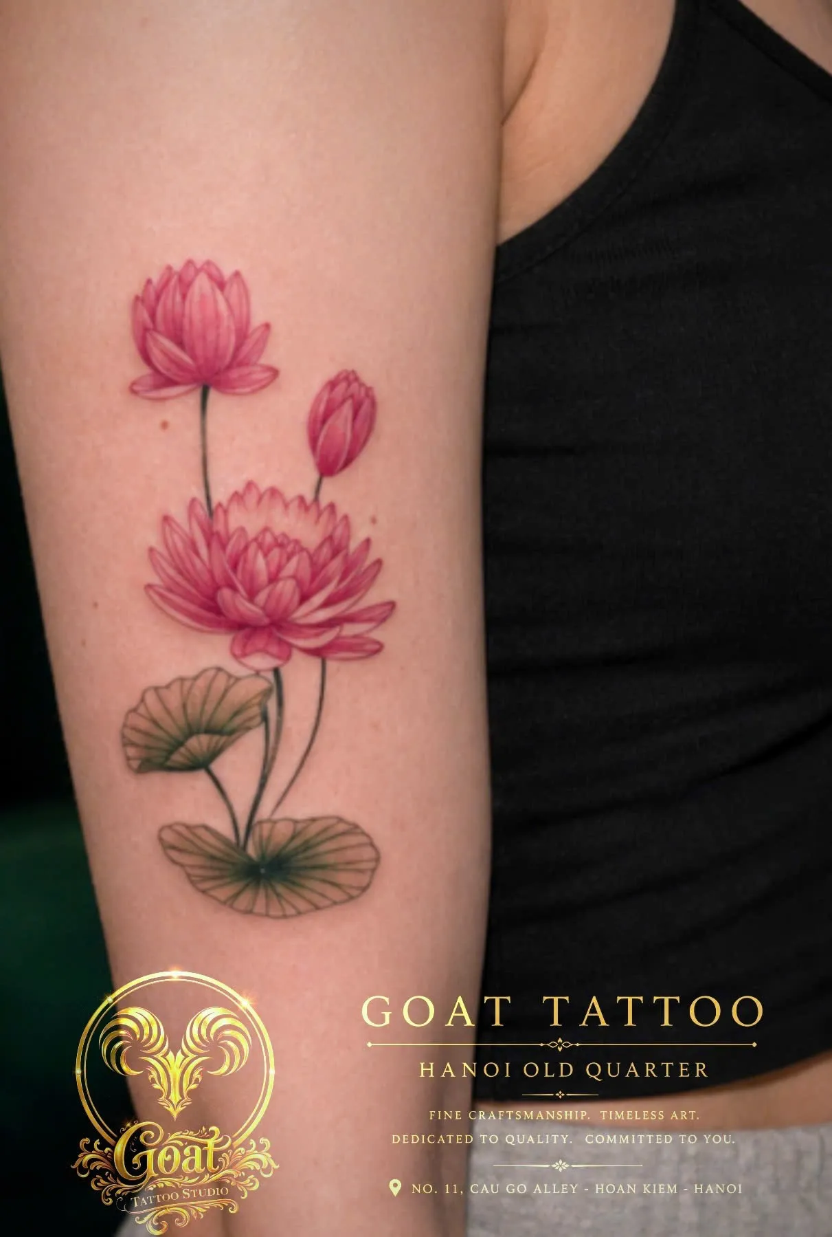 Color illustrative pink lotus flowers with lily pads tattooed along the upper arm, by GOAT Tattoo Studio in Hanoi.