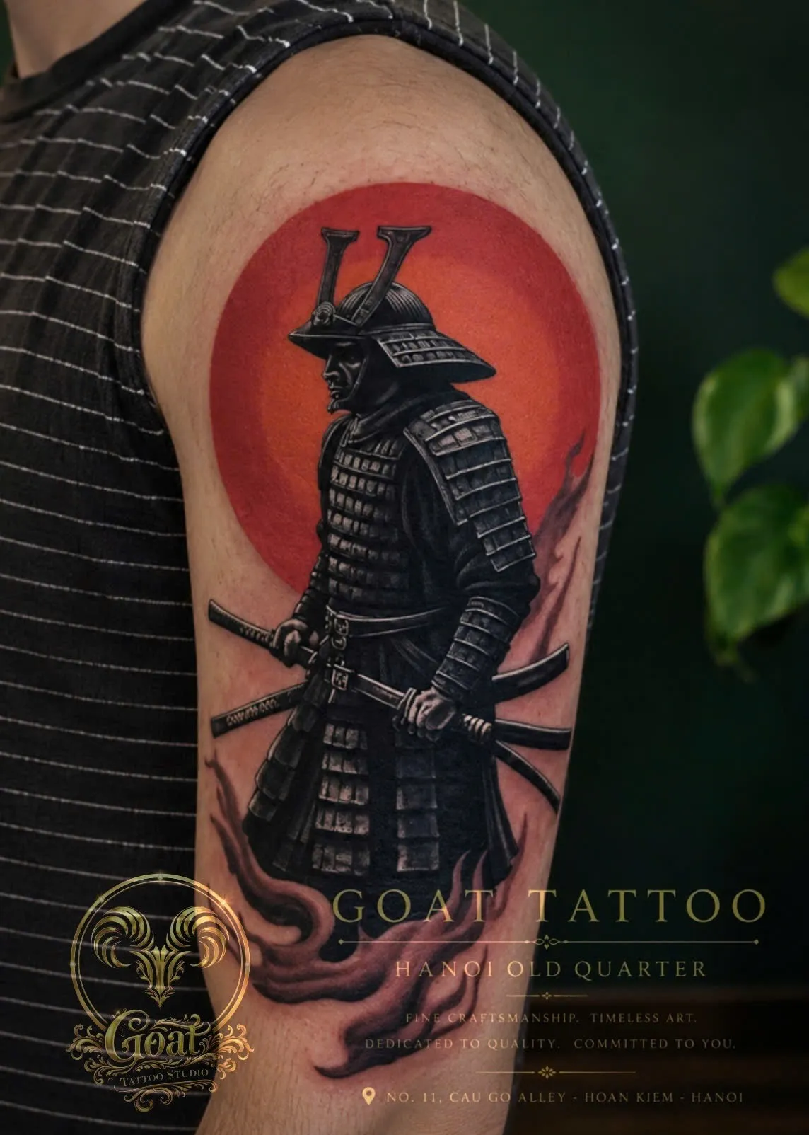 Color Japanese-style samurai tattoo with a bold red sun backdrop, on the upper arm, by GOAT Tattoo Studio Hanoi.