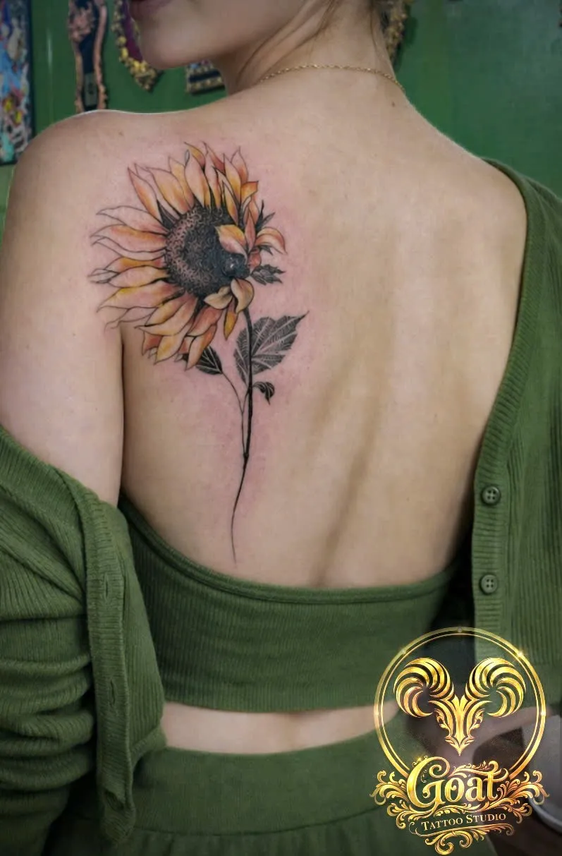 Illustrative color sunflower tattoo with painterly shading on the shoulder blade, by GOAT Tattoo Studio in Hanoi.