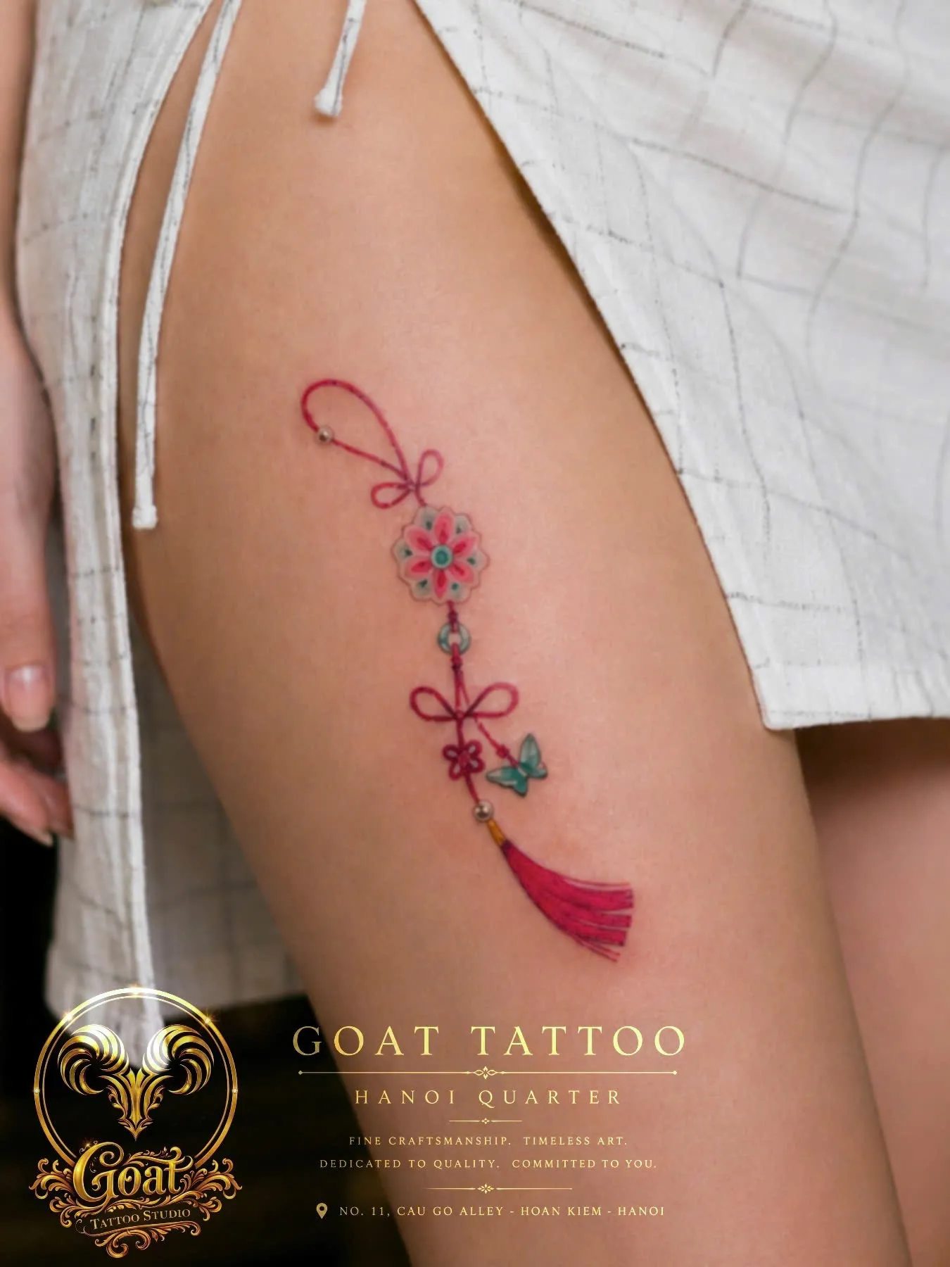 Color illustrative tassel ornament tattoo with flower and butterfly detail on the thigh, by GOAT Tattoo Studio, Hanoi.