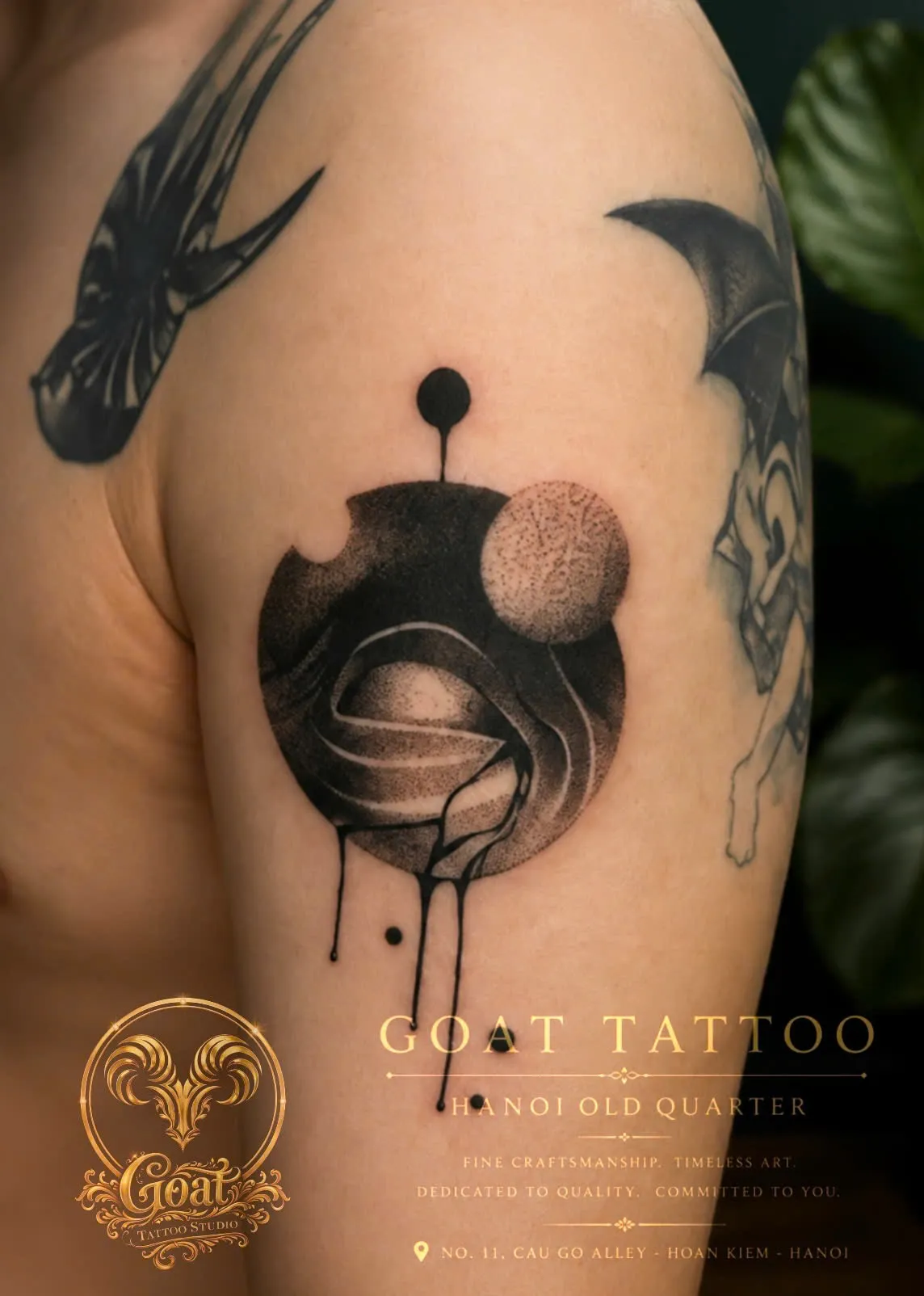 A striking dotwork tattoo of abstract shaded orbs with dripping ink accents on the upper arm, done at GOAT Tattoo Studio in Hanoi's Old Quarter.