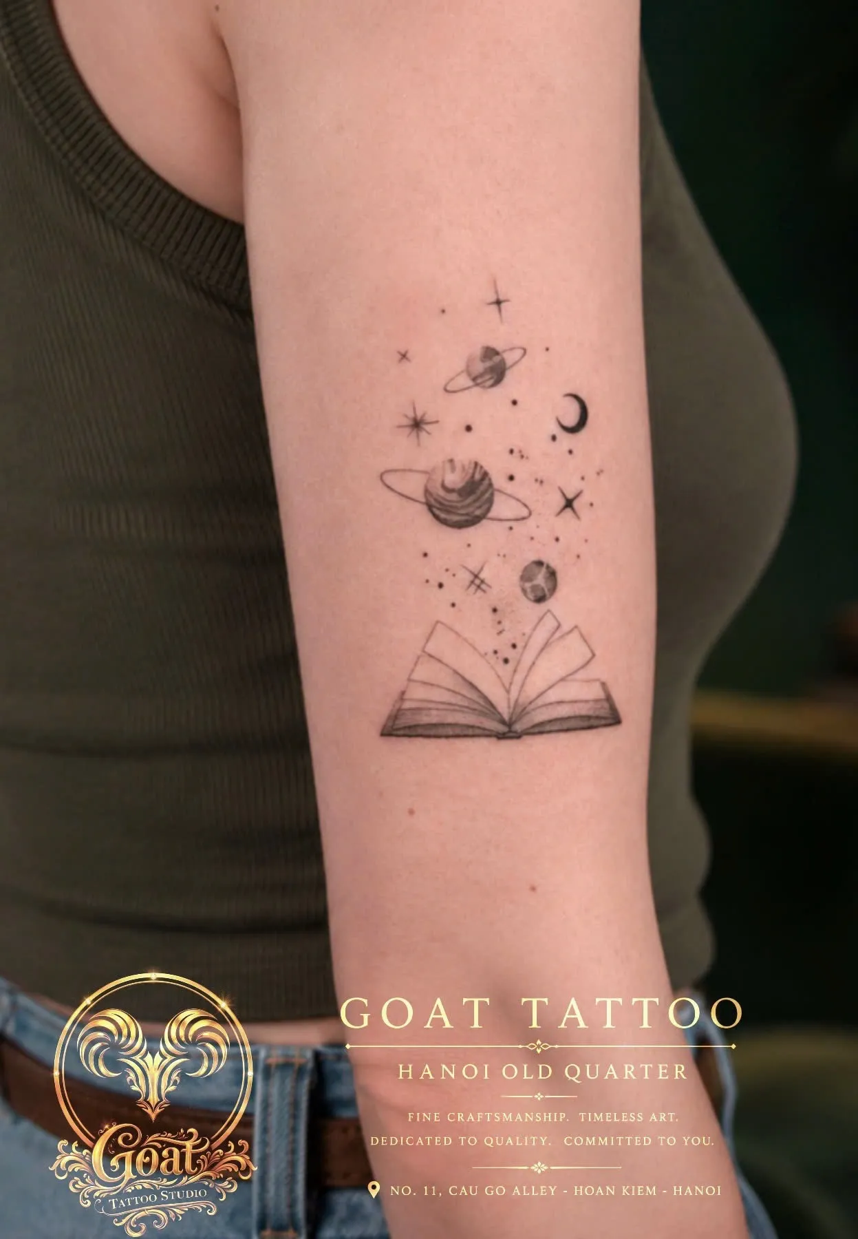 Fine line tattoo of an open book releasing stars and planets, inked on the forearm, GOAT Tattoo Studio Hanoi.