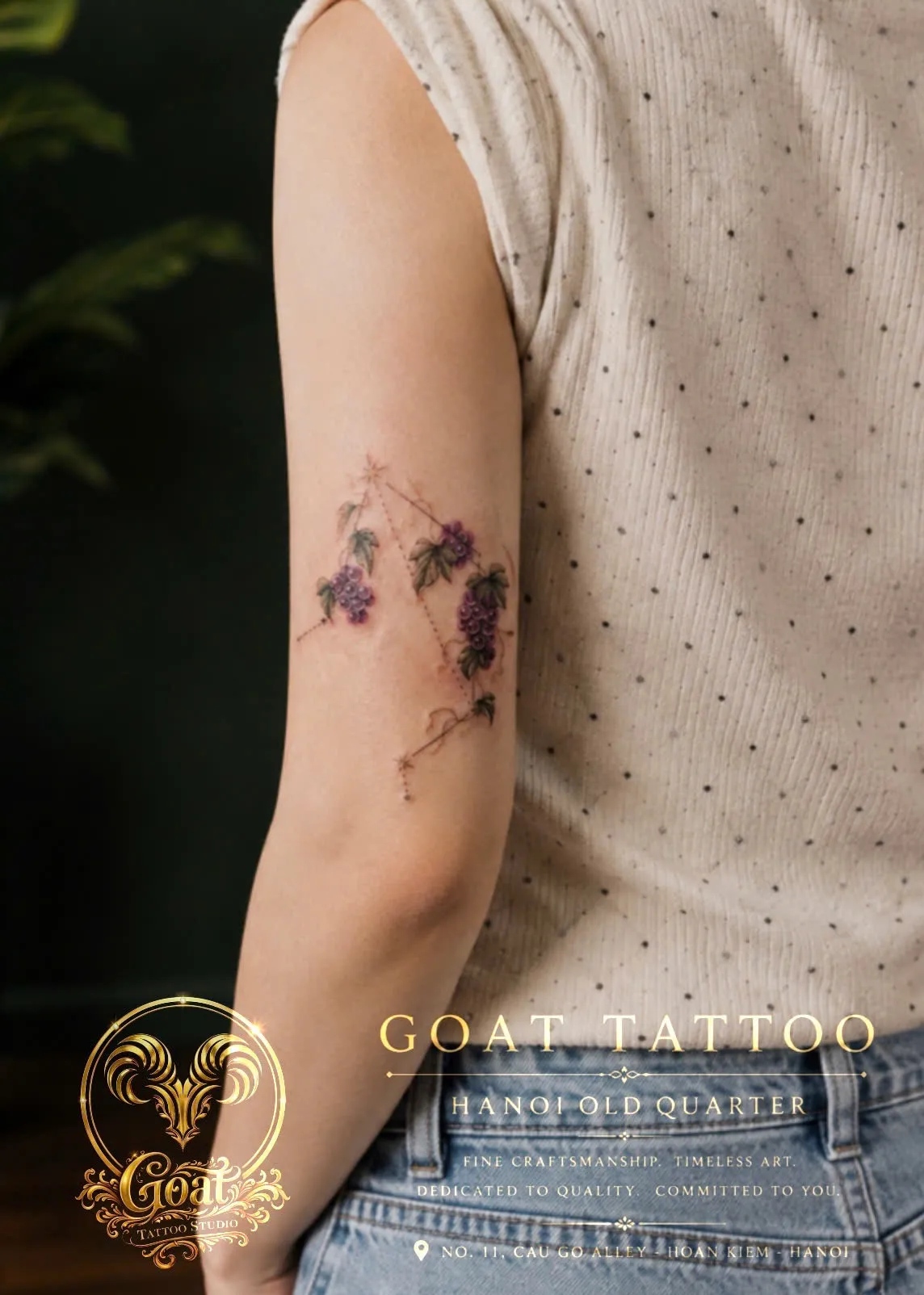 Fine line tattoo combining grape clusters and constellation dots on the upper arm, by GOAT Tattoo Studio in Hanoi.