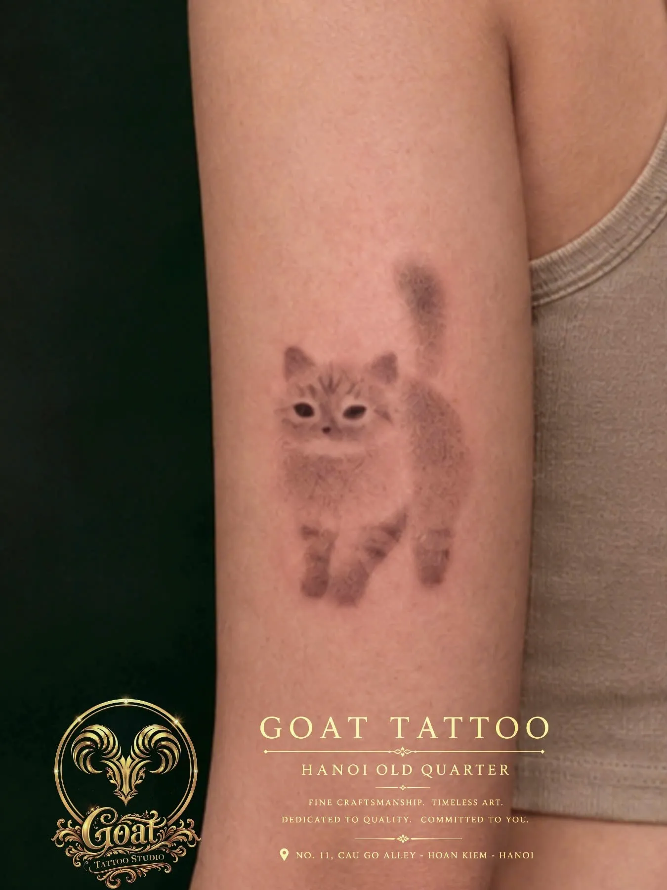 Soft minimalist cat tattoo rendered in grey wash on the forearm, GOAT Tattoo Studio Hanoi.