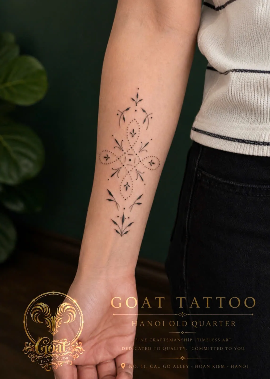 A fine line ornamental cross-shaped tattoo with dotwork florals on the forearm, by GOAT Tattoo Studio Hanoi.