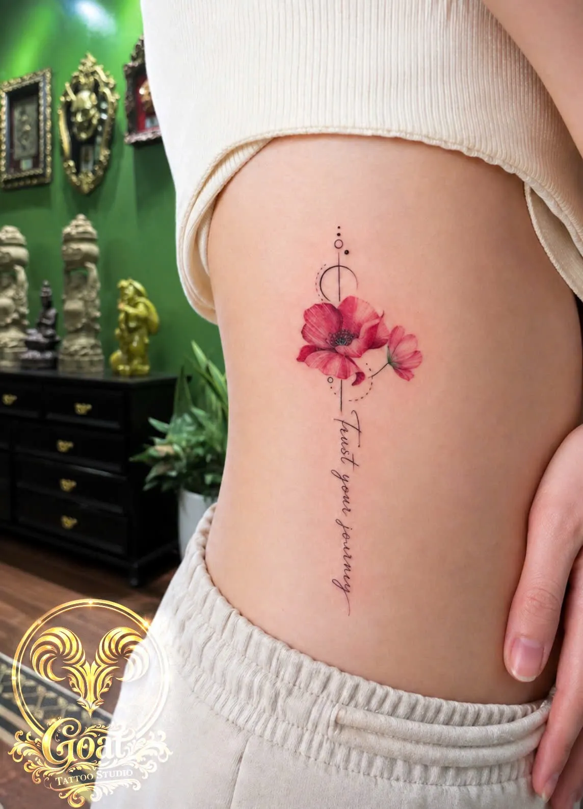 Fine line poppy flowers with 'Trust your journey' script tattooed along the rib cage, by GOAT Tattoo Studio Hanoi.