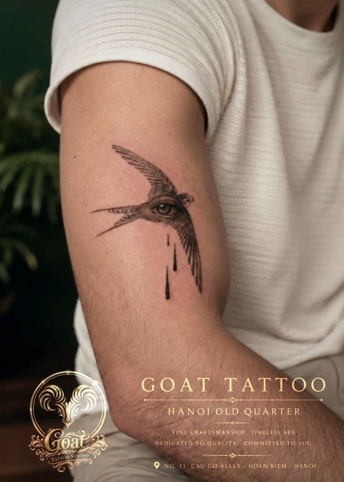 Fine line blackwork swallow tattoo featuring a detailed eye motif on the upper arm, GOAT Tattoo Studio Hanoi.
