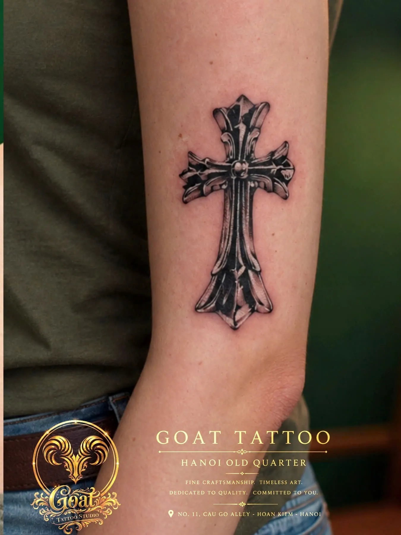 Black and grey ornate gothic cross tattoo with detailed shading on the forearm, GOAT Tattoo Studio Hanoi.