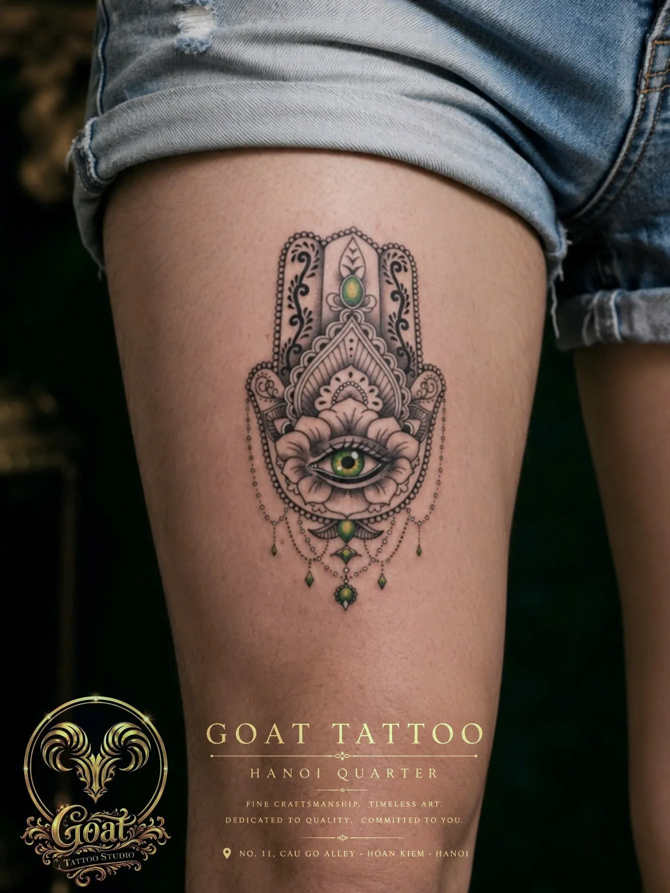 Detailed black and grey hamsa hand tattoo with eye and gemstone accents on the thigh, by GOAT Tattoo Studio, Hanoi.