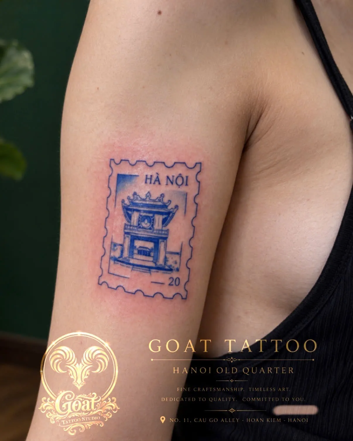 A blue postage-stamp style tattoo of Hanoi's Temple of Literature gate, on the upper arm, by GOAT Tattoo Studio in Hanoi's Old Quarter.