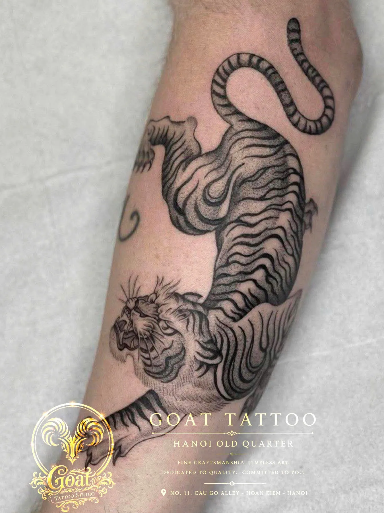 Black and grey Japanese-style tiger tattoo climbing along the forearm, by GOAT Tattoo Studio in Hanoi's Old Quarter.