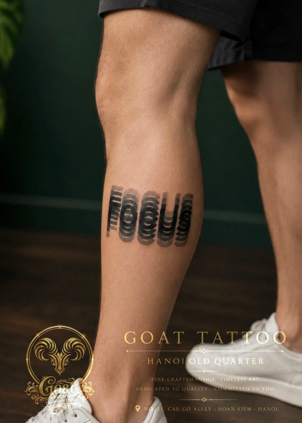 Bold typographic lettering tattoo reading 'FOCUS' on the calf, by GOAT Tattoo Studio in Hanoi.