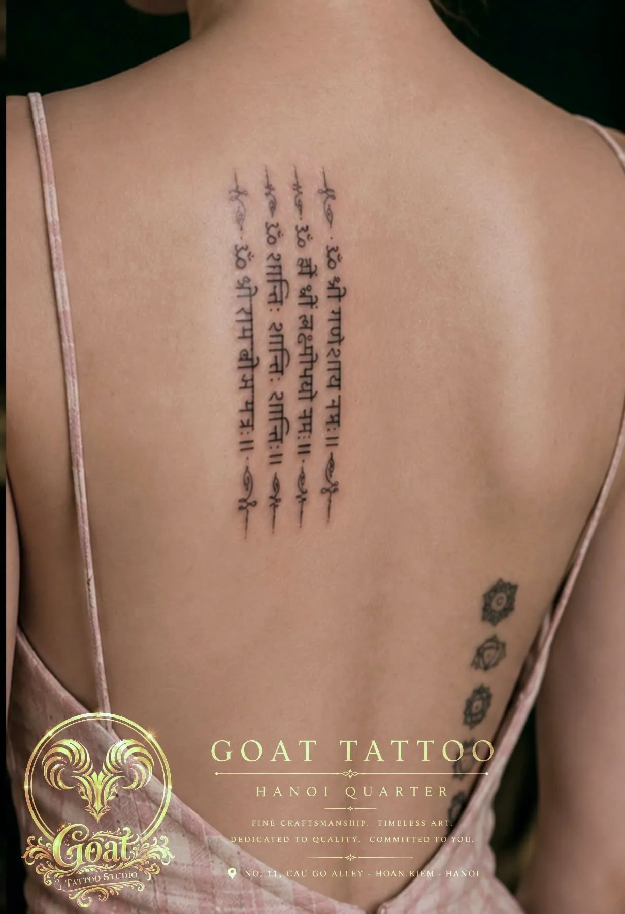 Vertical Sanskrit script mantra tattoo running along the spine, by GOAT Tattoo Studio in Hanoi's Old Quarter.