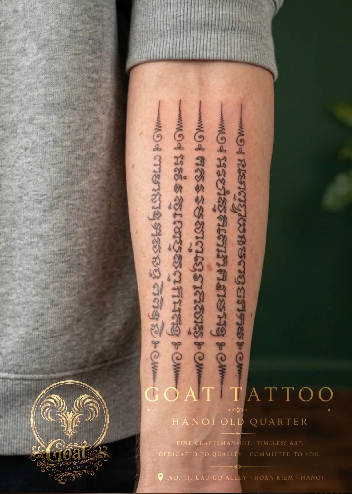 Traditional Thai sak yant sacred script tattooed in six columns down the forearm, by GOAT Tattoo Studio in Hanoi's Old Quarter.