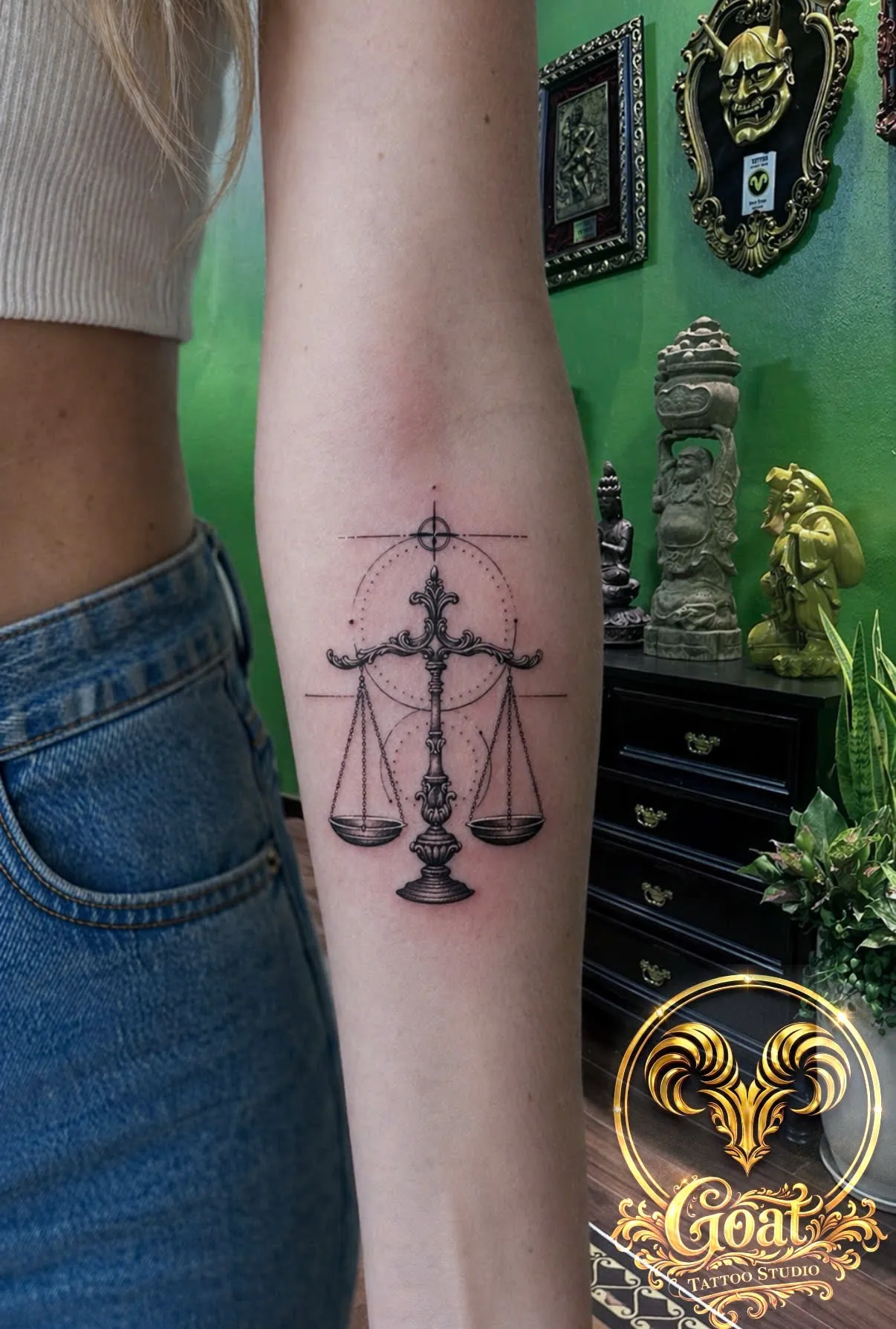 Detailed ornate scales of justice tattoo with geometric circle accents on the forearm, GOAT Tattoo Studio Hanoi.