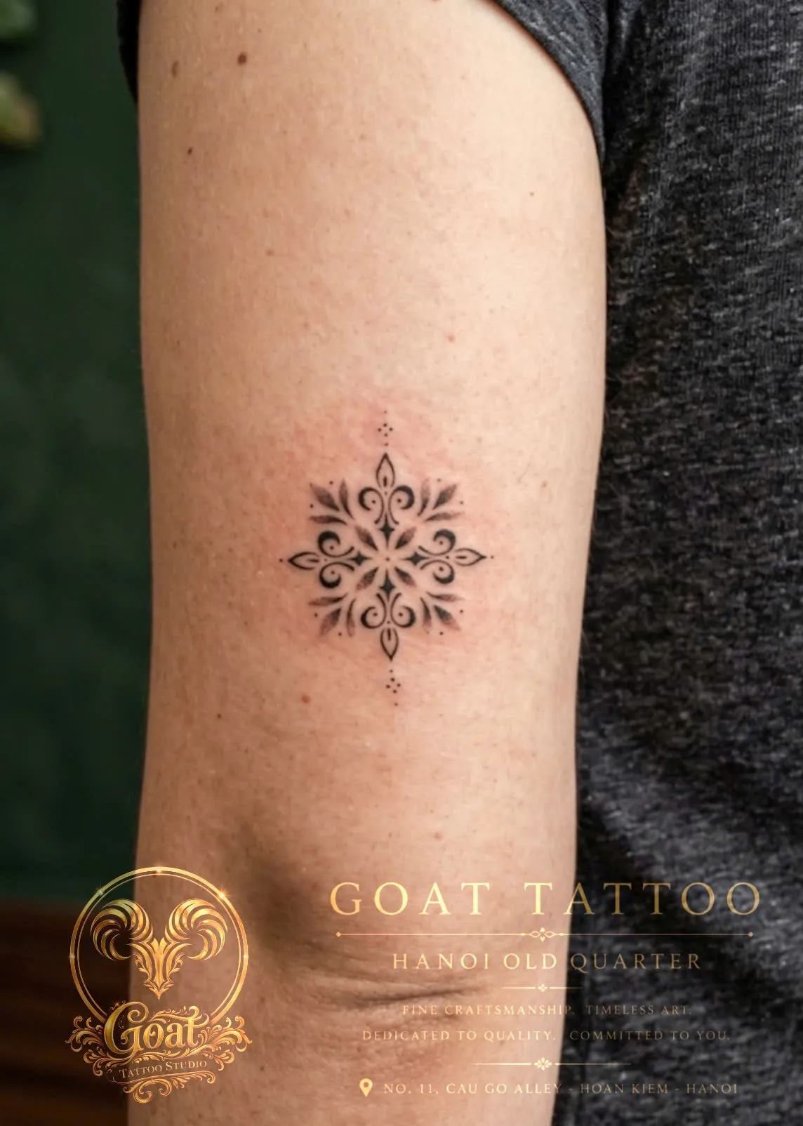 A small black ornamental snowflake-style tattoo on the upper arm, by GOAT Tattoo Studio in Hanoi's Old Quarter.