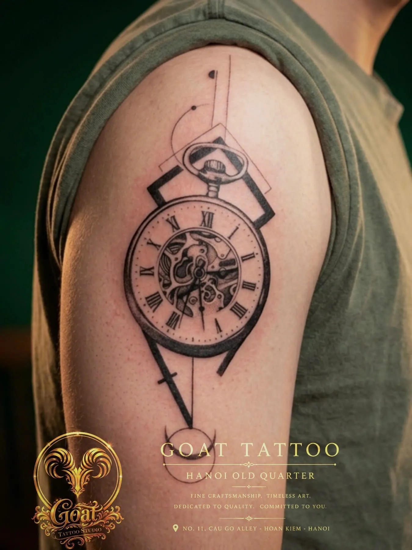 Black and grey realistic pocket watch tattoo with pendulum and exposed gears on the upper arm, by GOAT Tattoo Studio in Hanoi.