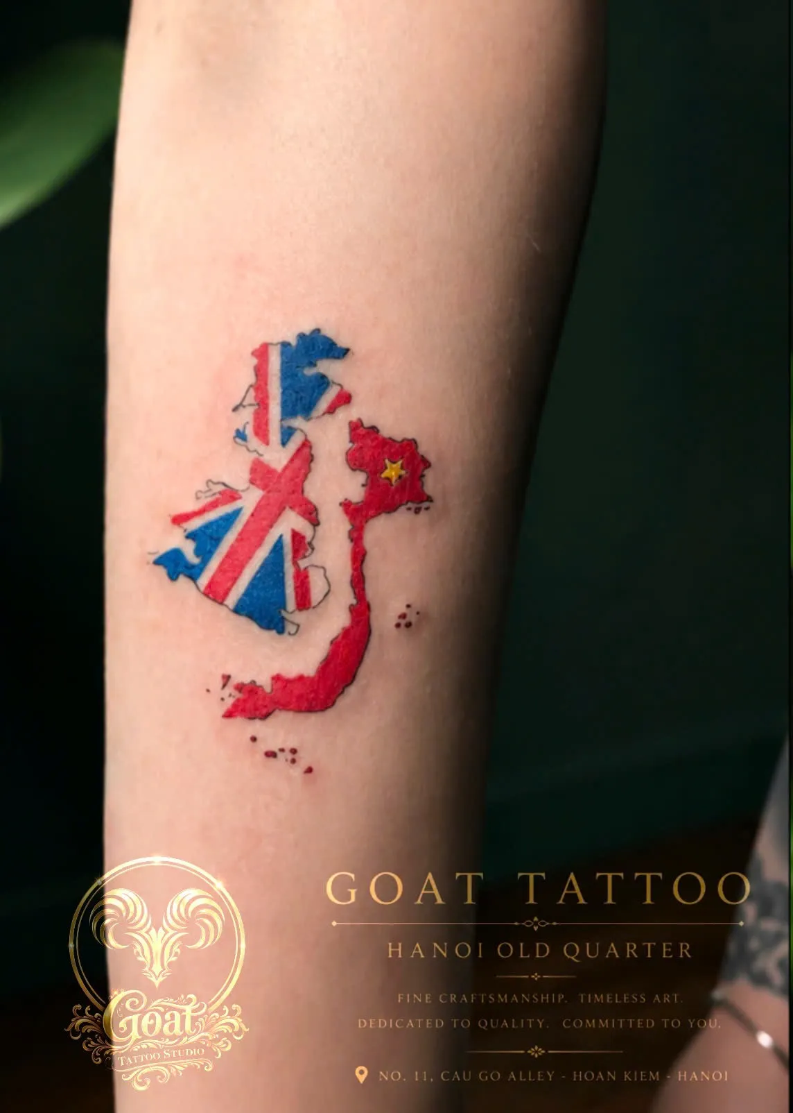 A vibrant color forearm tattoo merging the outlines of the United Kingdom and Vietnam filled with their national flags, done at GOAT Tattoo Studio in Hanoi's Old Quarter.