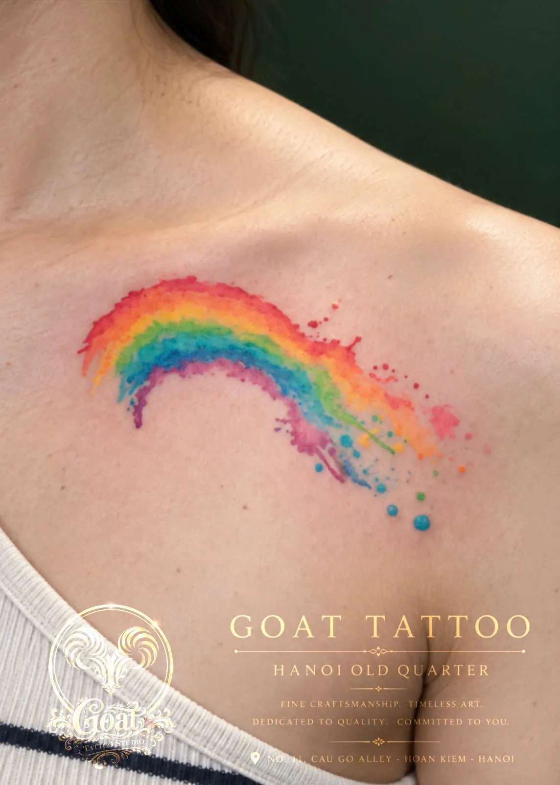 A vivid watercolor-style rainbow splash tattoo across the collarbone, by GOAT Tattoo Studio in Hanoi's Old Quarter.