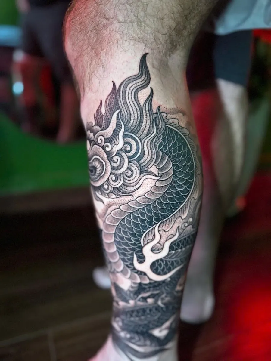 Black and grey dragon tattoo on the calf, photo shared by the reviewer